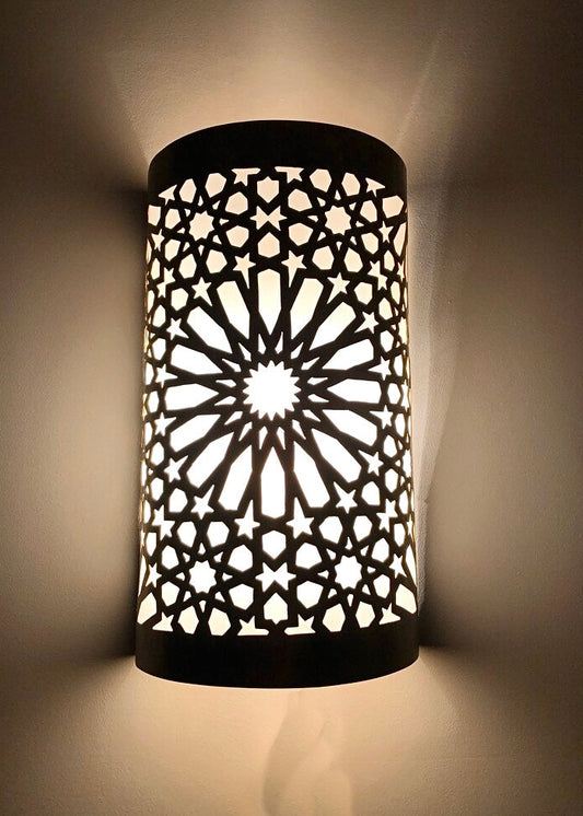 Handmade Moroccan brass wall lamp with intricate geometric cutouts casting warm shadows.