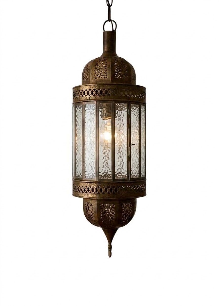 A hanging lantern-style brass pendant light with ornate cutout metal detailing and clear textured glass panels, shown against a plain white background.