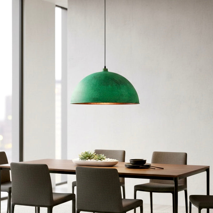 Industrial style copper pendant lamp with green verdigris finish in a minimalist modern dining room.