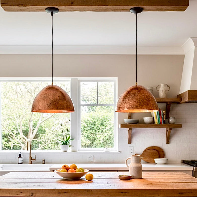 Two modern dome copper pendant lights in a rustic farmhouse kitchen.