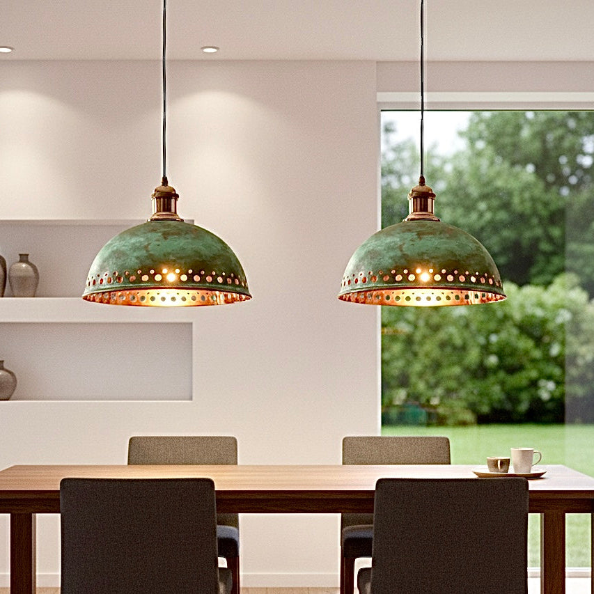 Large dome-shaped verdigris lamp with a reflective gold interior centered over a luxury dining table with floral decor.