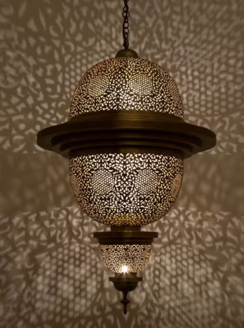 Large handmade Moroccan brass ceiling lamp casting intricate shadow patterns.