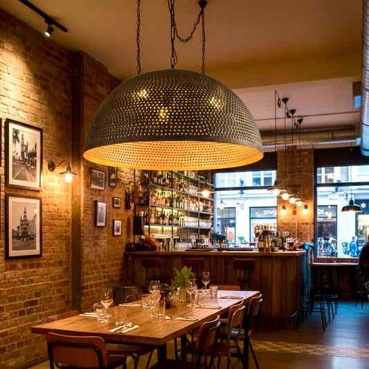 Large Moroccan handmade brass pendant lamp in black finish for rustic restaurant interior design.