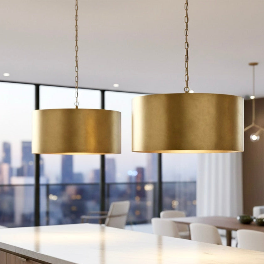 Contemporary gold drum chandelier centerpiece above a luxury wooden dining table in a high-ceiling room.