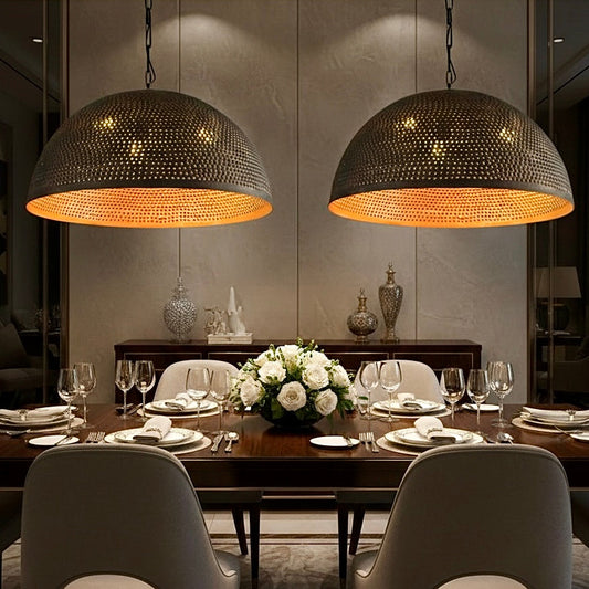Elegant dining room featuring two oversized black handmade brass dome lamps with gold lining.
