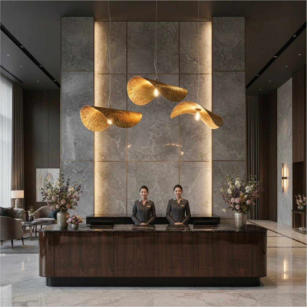 Large sculptural gold pendant lamps above a dark wood reception desk in a luxury marble lobby.