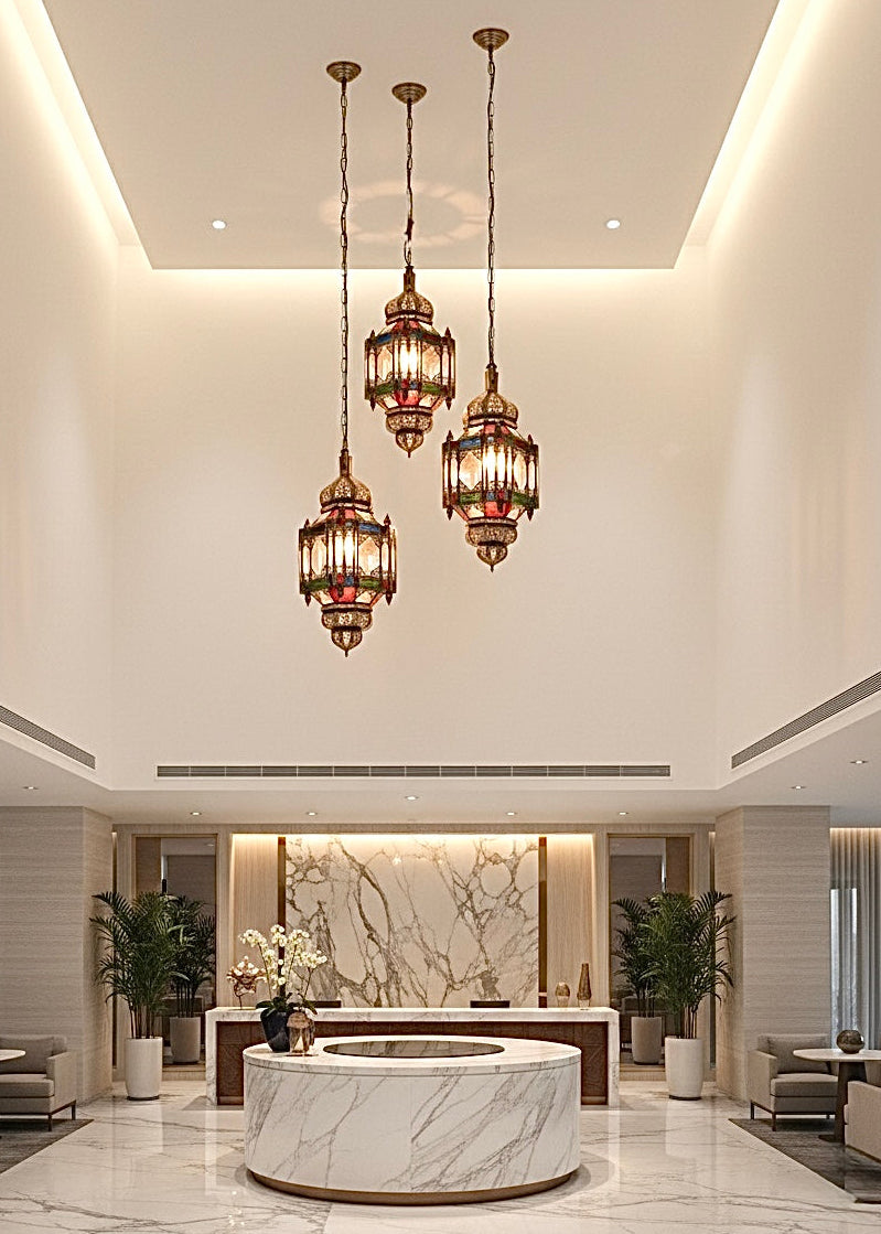 A set of three hanging Moroccan brass and stained glass pendant lamps in a luxury hotel lobby.