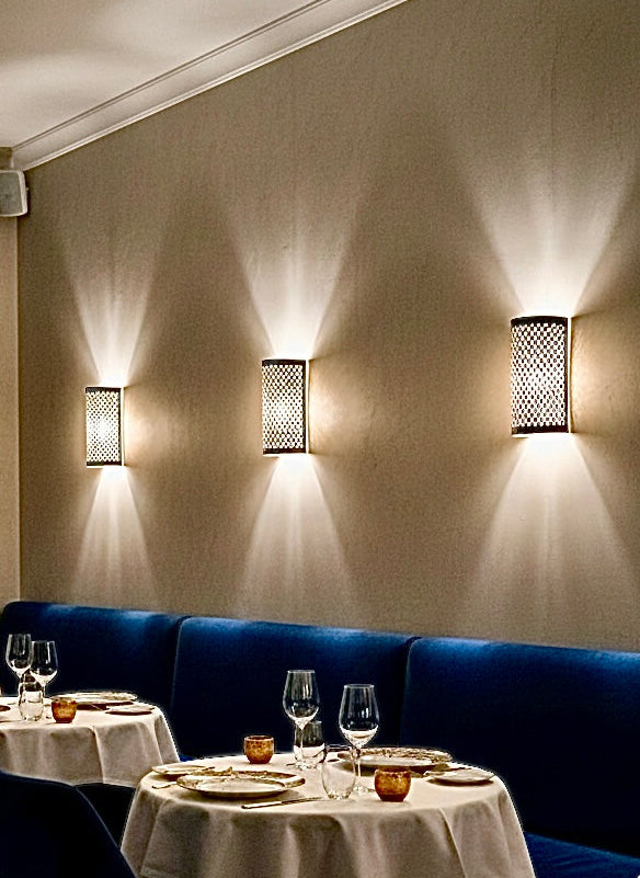 Three luxury brass Moroccan wall lamps illuminating a blue booth in a modern restaurant.