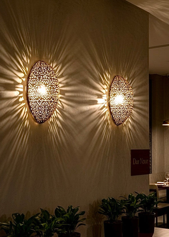 Multiple Moroccan brass wall lamps used in a luxury restaurant setting for an exotic and warm ambient lighting effect.
