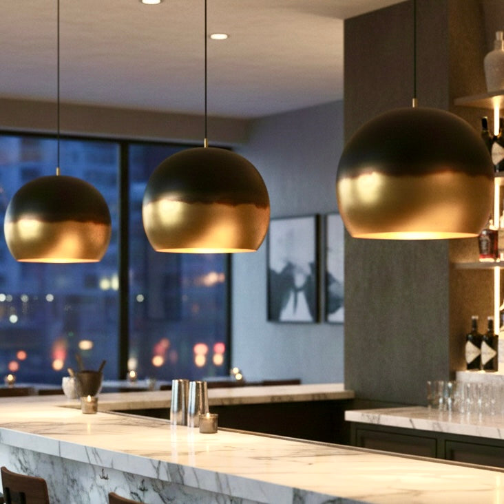 Mida-century modern inspired brass dome pendant hanging above a wooden coffee table in a bright room.
