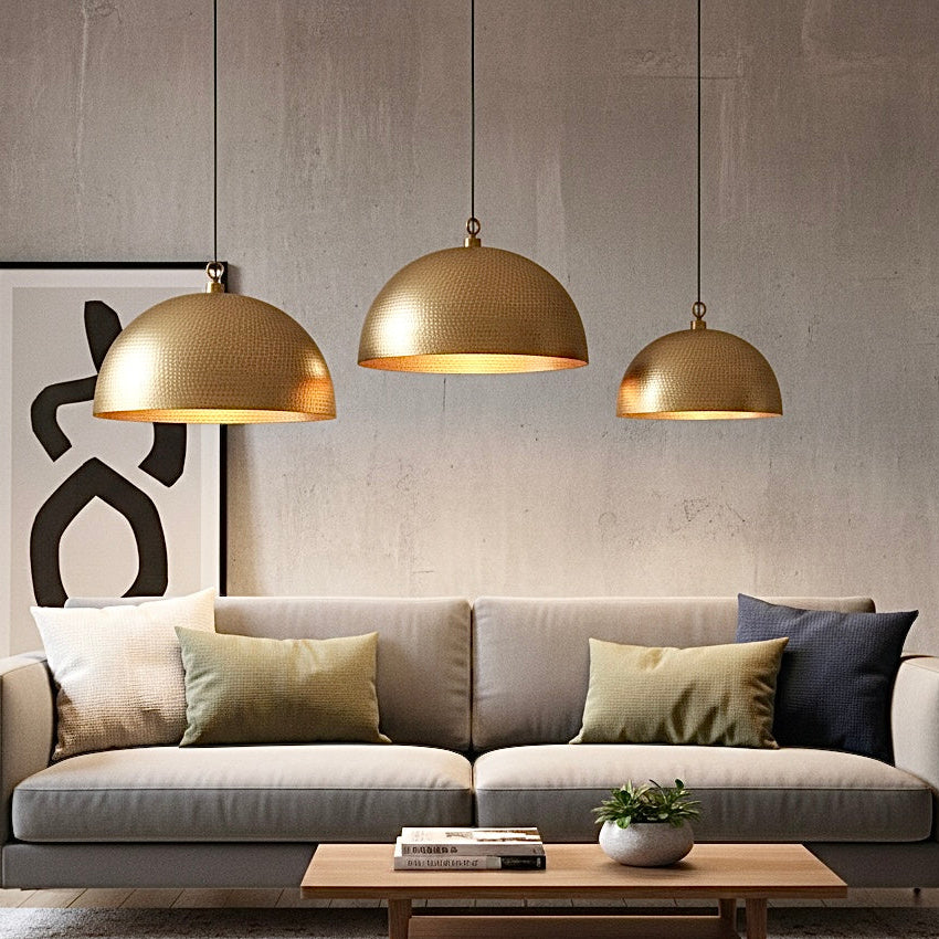 Minimalist hammered brass pendant light in a clean, modern white interior setting.
