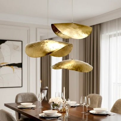 Minimalist handcrafted gold brass pendant light hanging in a high-ceiling living room
