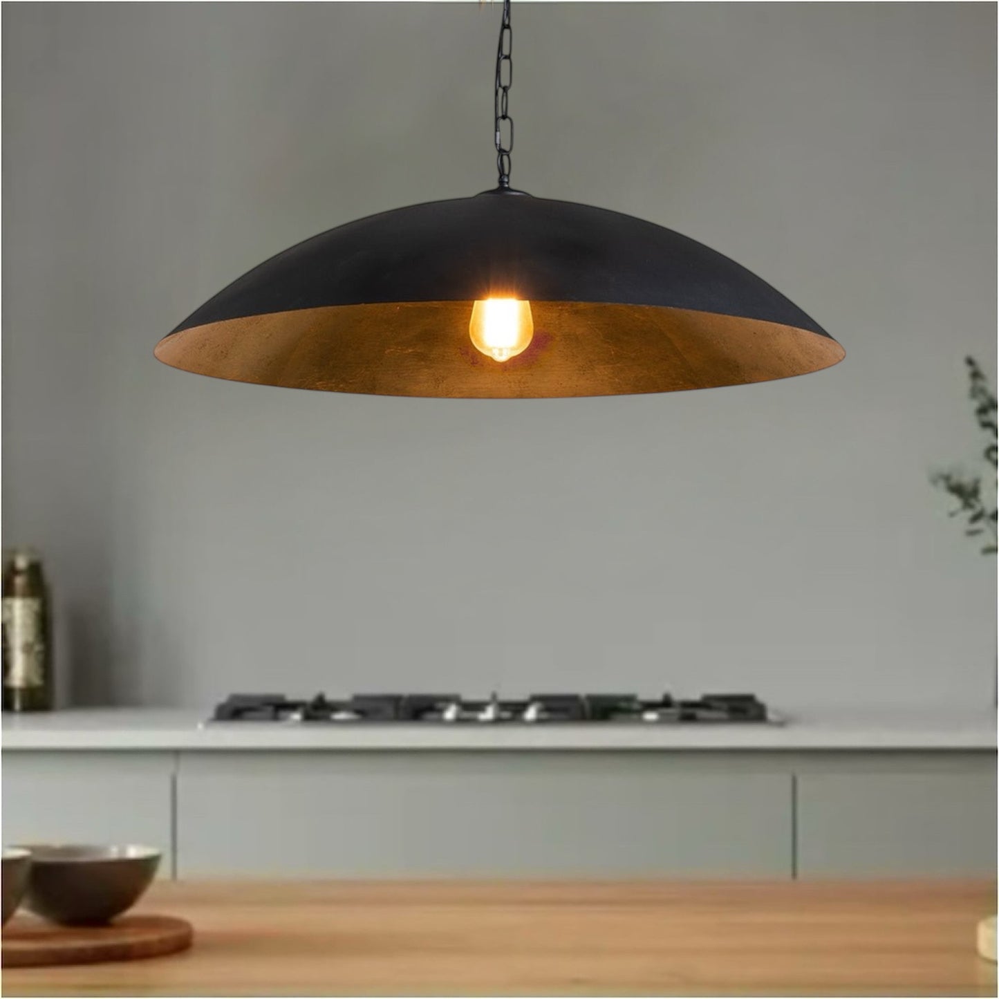 Industrial black pendant light with gold interior hanging over a modern kitchen counter.