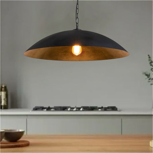 Industrial black pendant light with gold interior hanging over a modern kitchen counter.