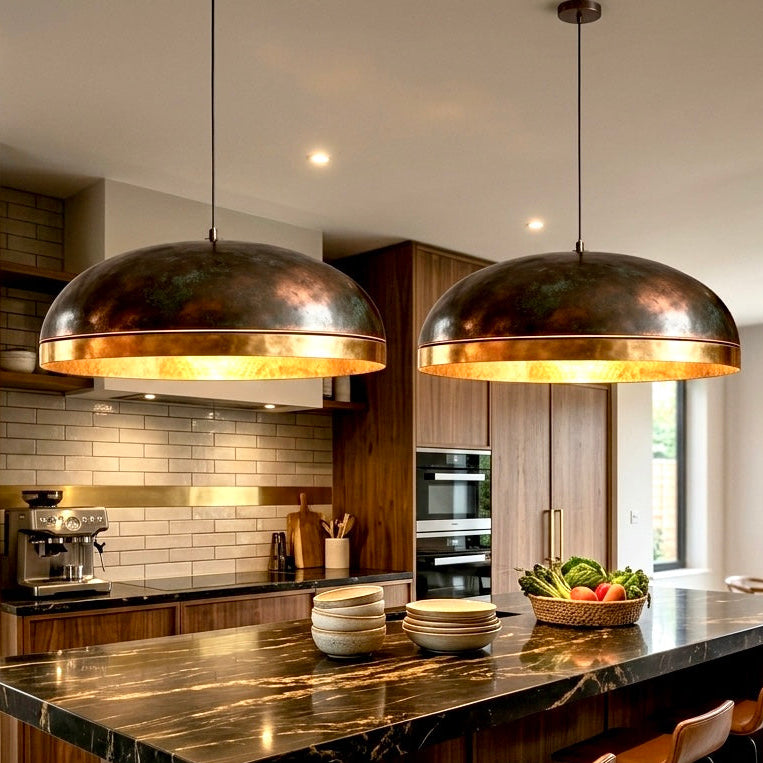 Pair of modern dome pendant lights in antique brass installed over a luxury marble kitchen island.