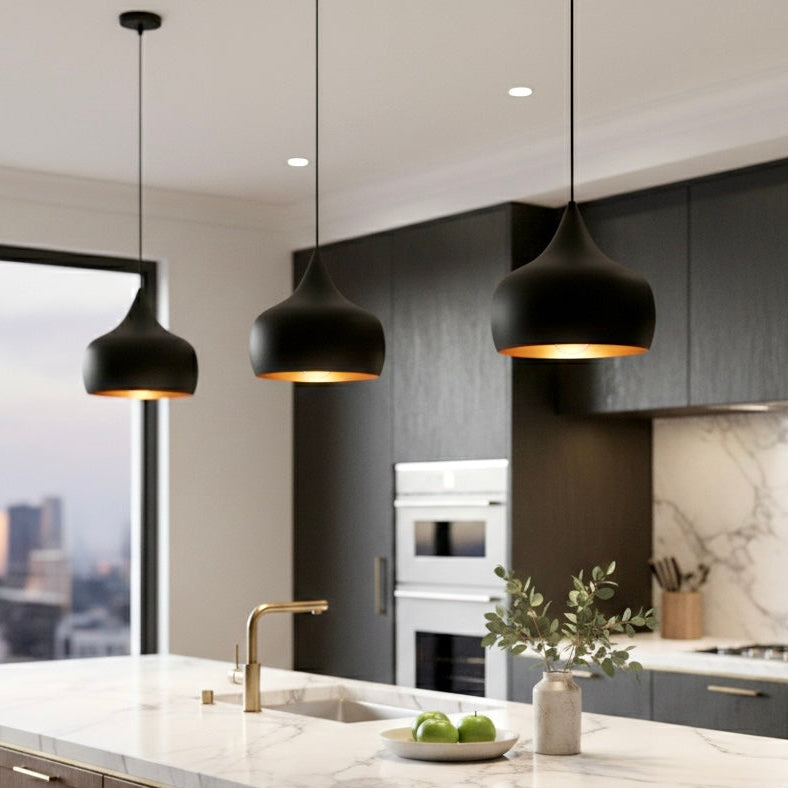 Trio of handmade black and gold dome pendant lights over a modern marble kitchen island.