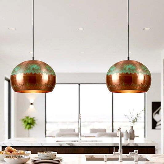 Two modern copper pendant lights with a green patina oxidation finish hanging over a kitchen island.