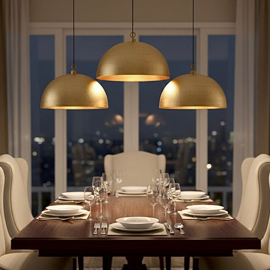 Trio of hammered brass dome lights hanging over a modern wooden dining table.
