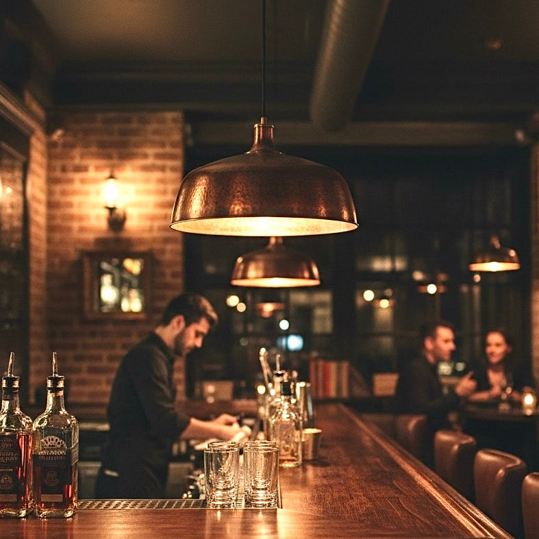 Modern hammered copper dome pendant lighting over a rustic wooden bar counter.