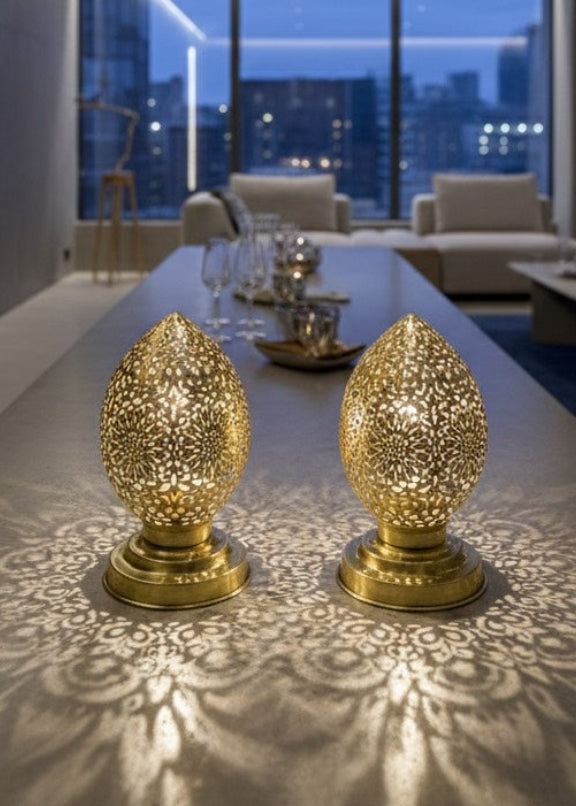  Two golden Moroccan lamps on a long grey table in a modern living room, casting beautiful patterns on the surface.