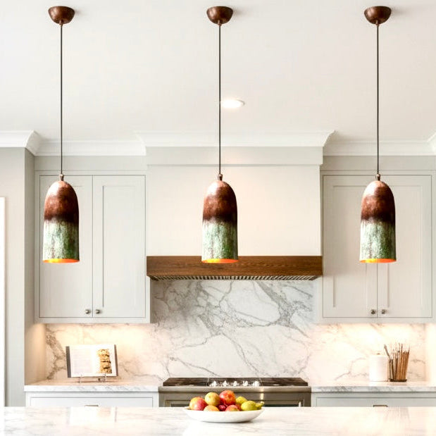 Set of three modern Moroccan verdigris copper lamps hanging over a marble kitchen island.