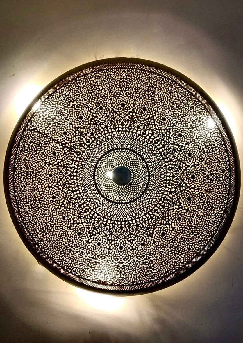 Close-up of a handmade Moroccan brass flush mount ceiling light showing intricate hand-engraved geometric patterns.