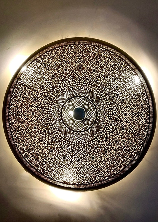 Close-up of a handmade Moroccan brass flush mount ceiling light showing intricate hand-engraved geometric patterns.
