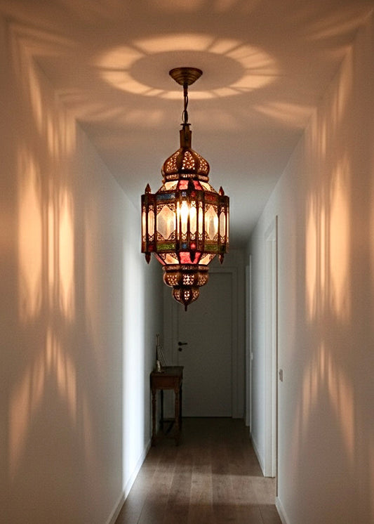 Traditional Moroccan brass and stained glass pendant light casting decorative shadows in a hallway.