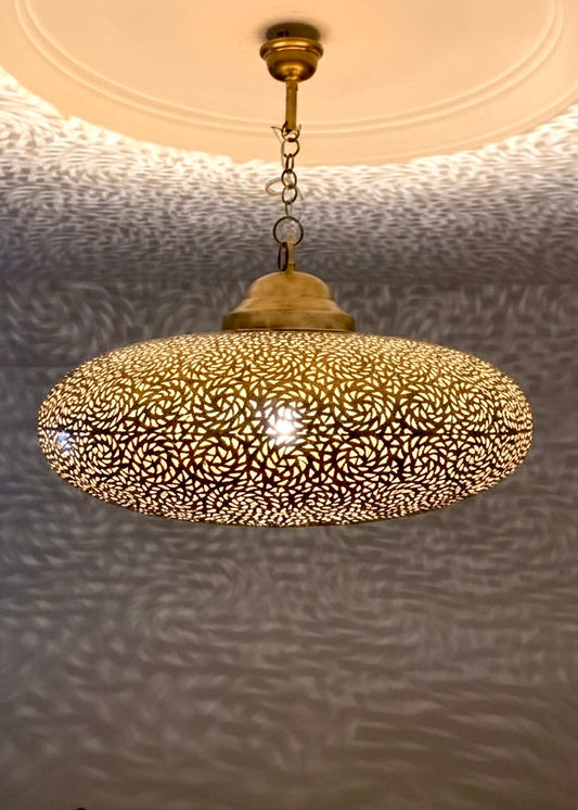 handmade Moroccan brass pendant lights hanging together, creating intricate floral shadow patterns on the ceiling and walls