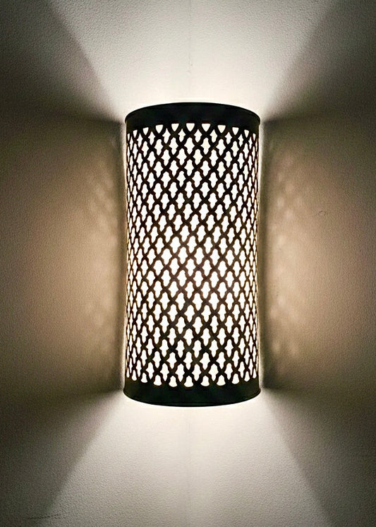 Stunning light effect of a brass Moroccan sconce casting decorative shadow patterns on a wall.