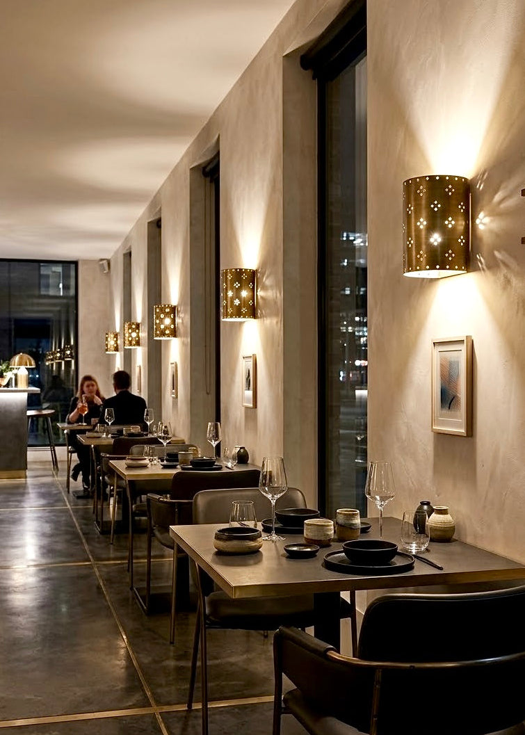 Modern Moroccan solid brass wall sconces installed along a luxury restaurant dining wall, creating warm ambiance for commercial hospitality projects.