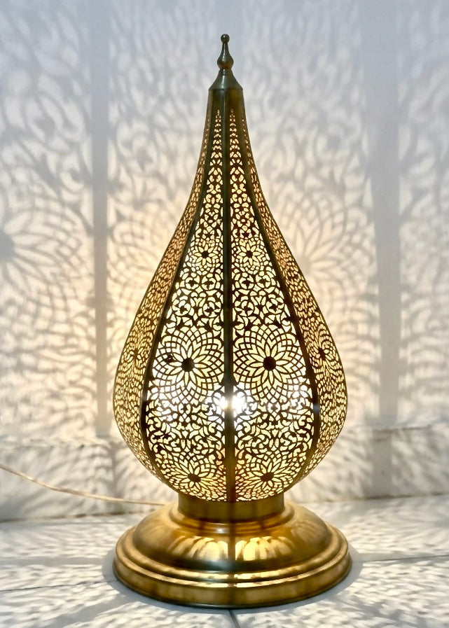 Handmade Moroccan brass table lamp creating beautiful shadow patterns on the wall.