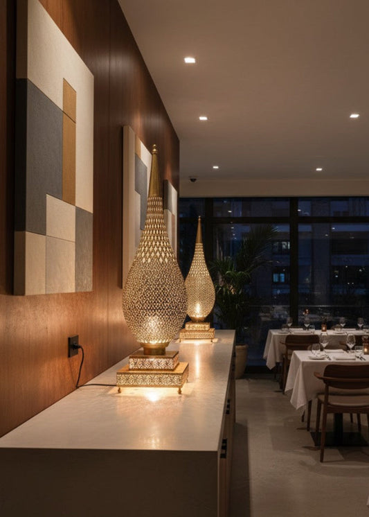 Pair of Moroccan brass table lamps on a sideboard in a modern, elegant restaurant with wood paneling and outdoor views.