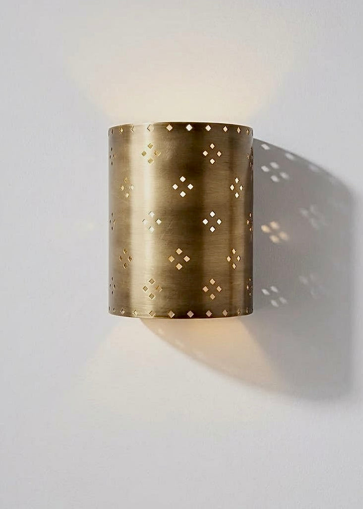 Handcrafted Moroccan brass wall sconce with geometric perforated pattern, emitting warm up-and-down ambient lighting for modern interiors