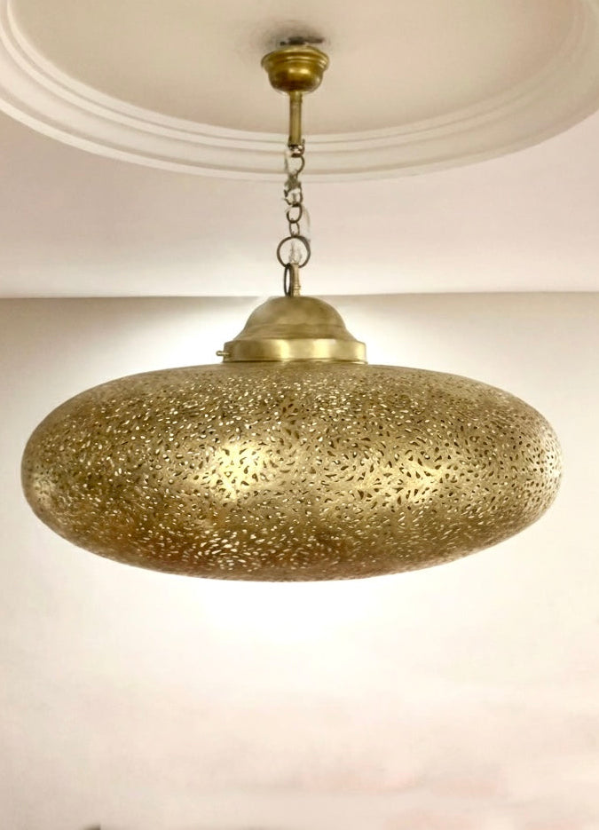 Large Moroccan chandelier hanging in a modern living room, casting warm exotic light and traditional shadow designs.