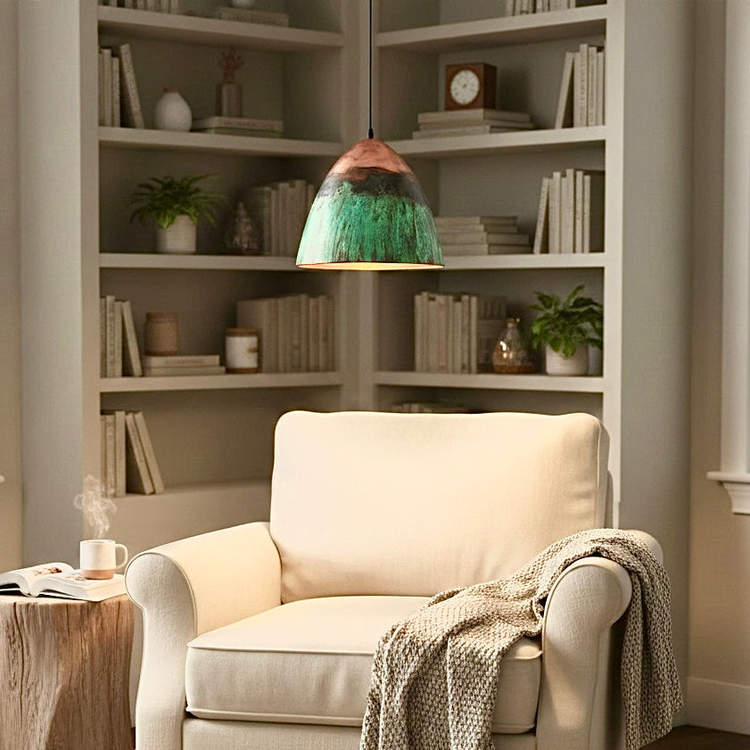 Handmade Moroccan dome pendant light in green patina and copper red hanging in cozy living room reading corner.
