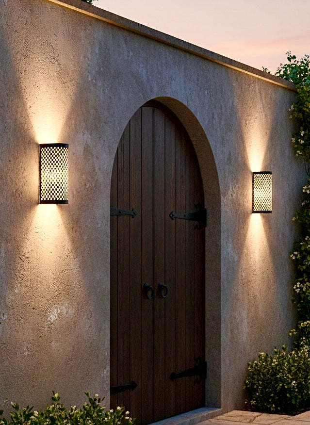 Brass Moroccan outdoor wall light fixture mounted on a rustic stone wall next to a wooden door.