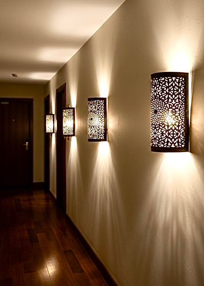 Brass Moroccan sconces lighting up a modern hallway, casting shadow patterns on the wall.