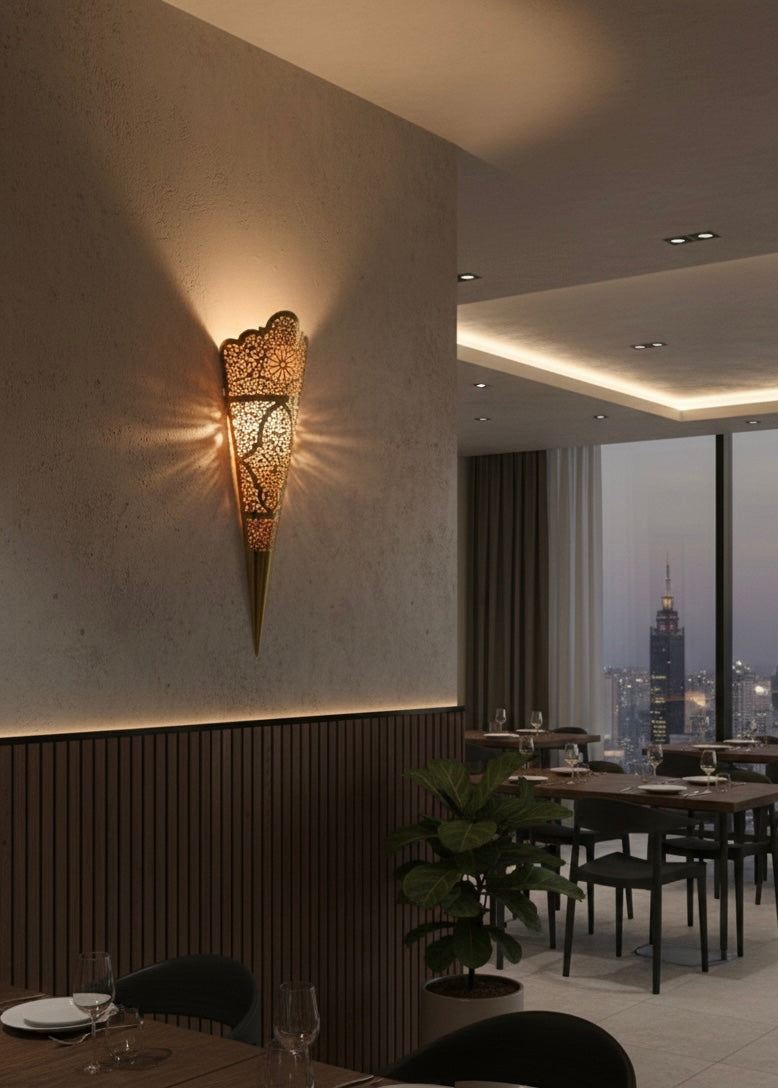 Moroccan brass wall light turned on, projecting beautiful ambient shadow patterns on a white wall.