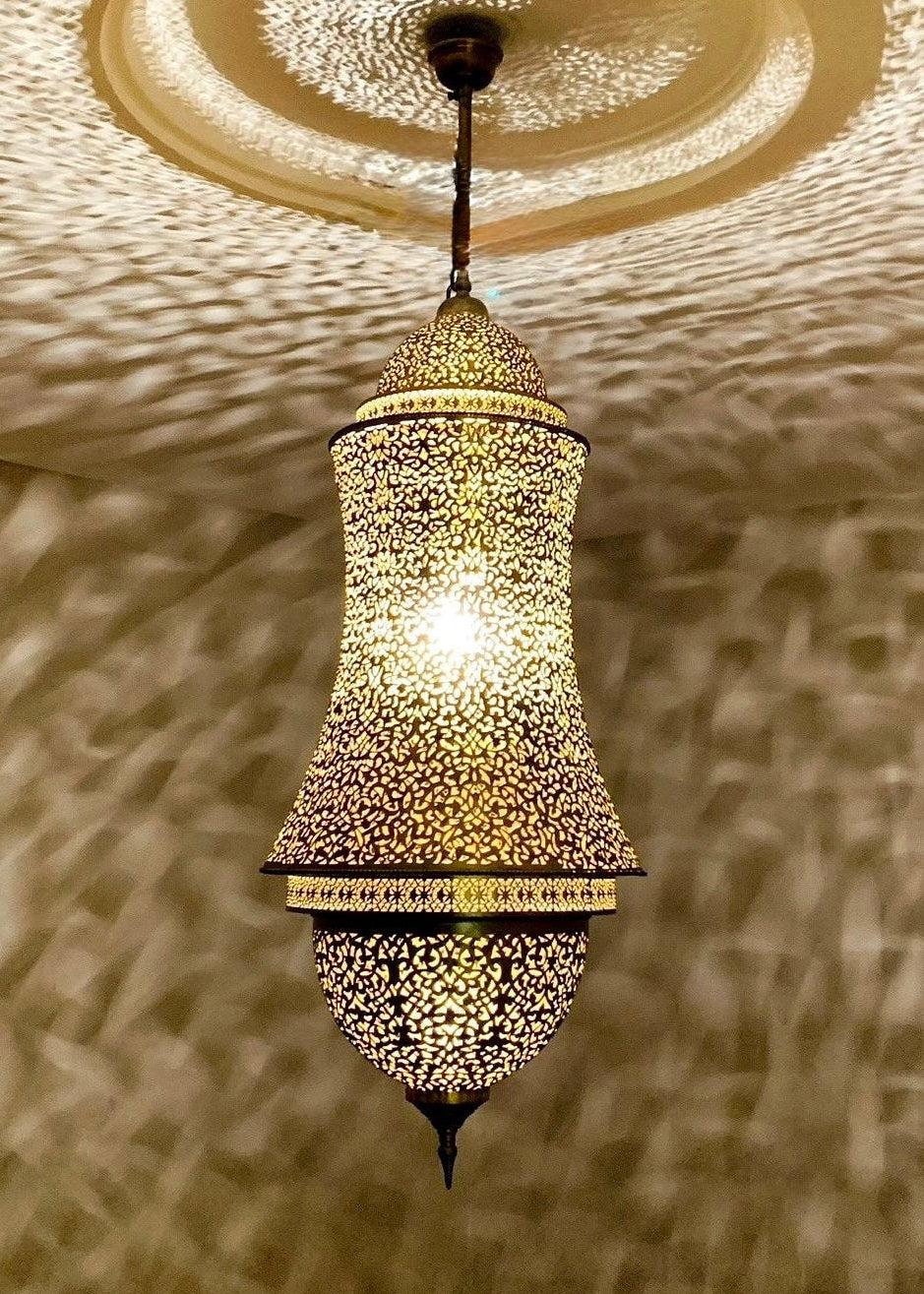 Oriental brass pendant light reflecting intricate artistic shadows on a white ceiling.