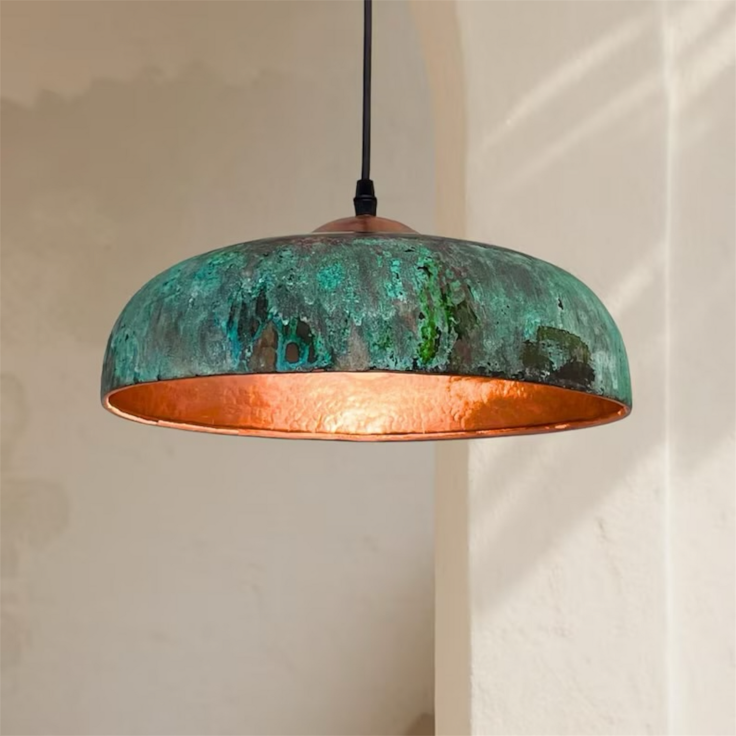 Bottom view of oxidized brass and copper dome pendant light showing warm ambient lighting
