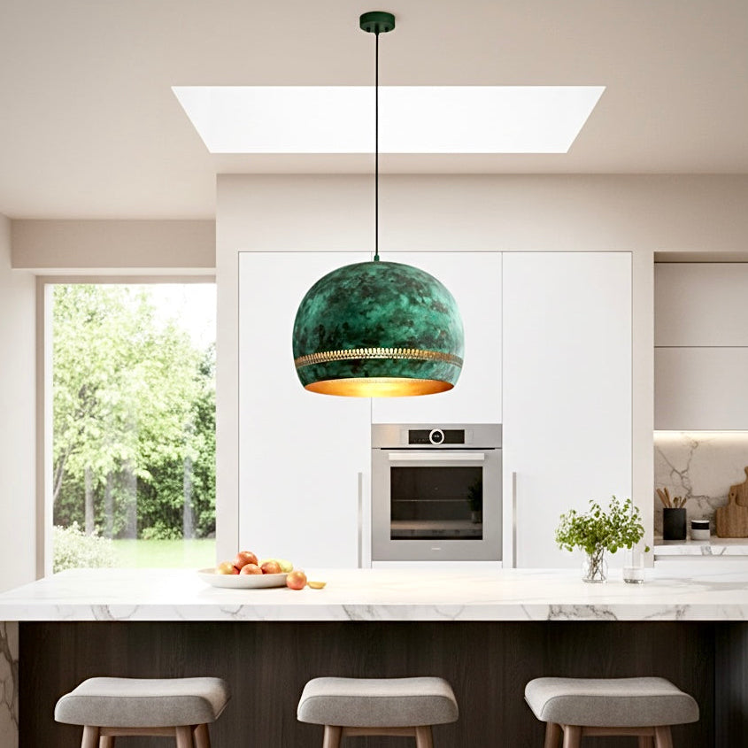 Single rustic brass green patina dome pendant light as a focal point in a sleek white kitchen with a dark wood breakfast bar.