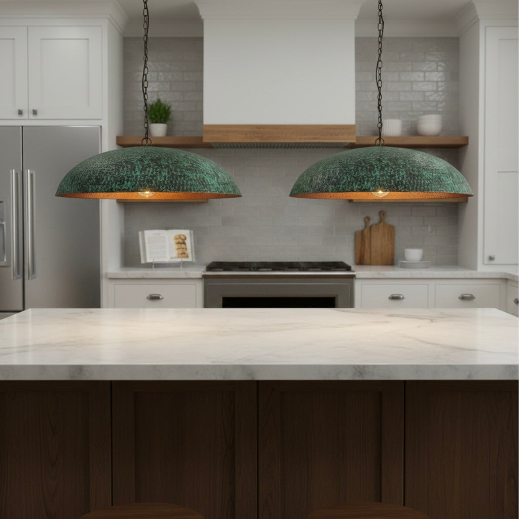 Two rustic verdigris green pendant lights hanging over a modern white marble kitchen island in a bright, contemporary kitchen.