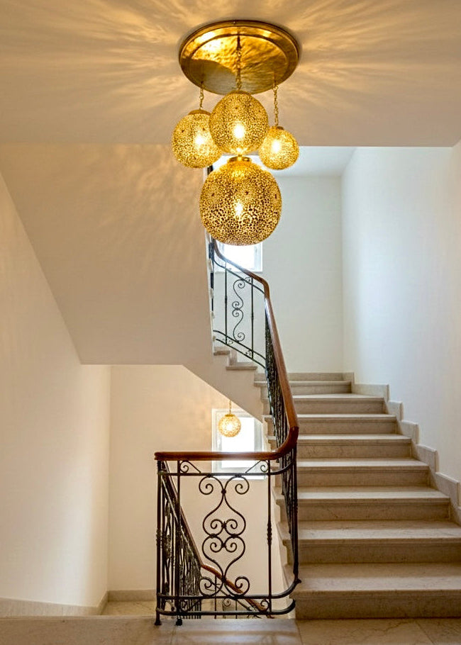 Bright white staircase illuminated by a decorative 4-globe Moroccan brass cluster pendant light.