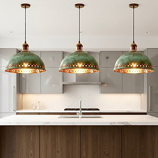 Set of three verdigris green patina dome lamps with gold lining hanging over a modern white kitchen island.