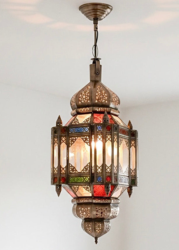 Close-up of a handmade Moroccan brass and stained glass light fixture with detailed metalwork.