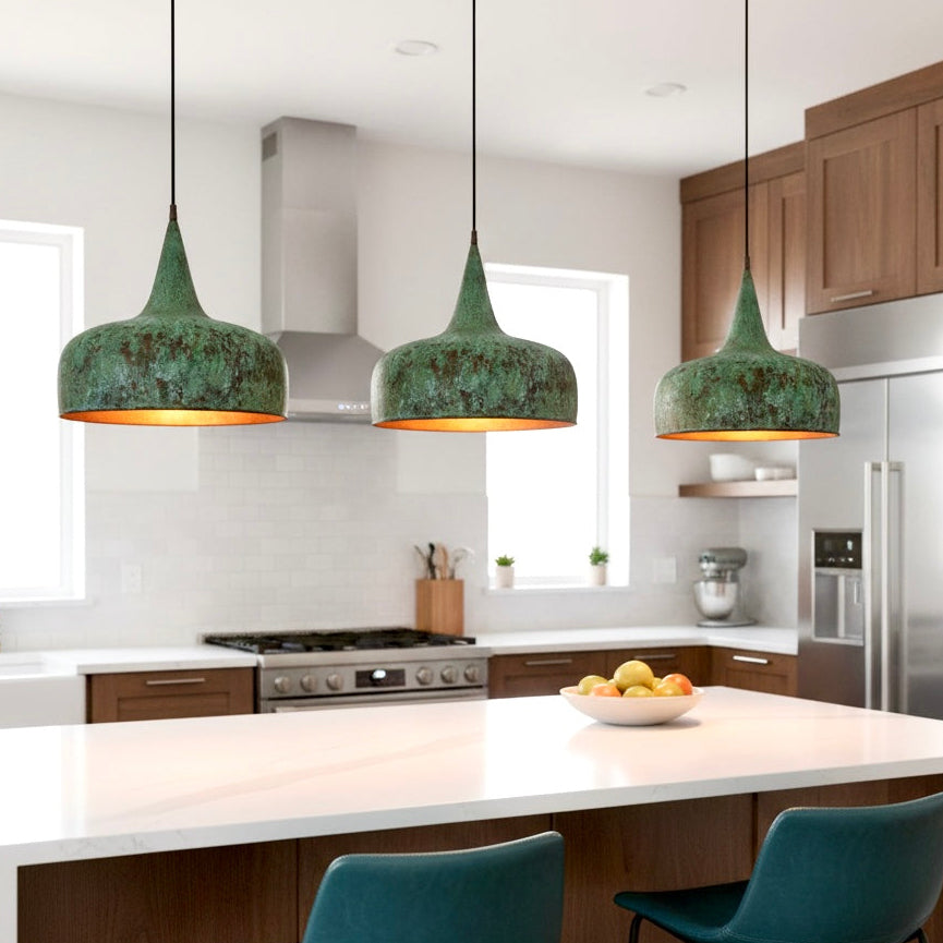 Three modern Moroccan green patina brass lamps hanging over a white marble kitchen island in a contemporary home.