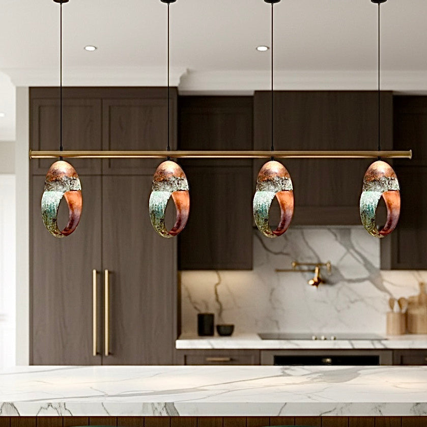 Set of four ring pendant lights in green patina brass above a contemporary kitchen island.