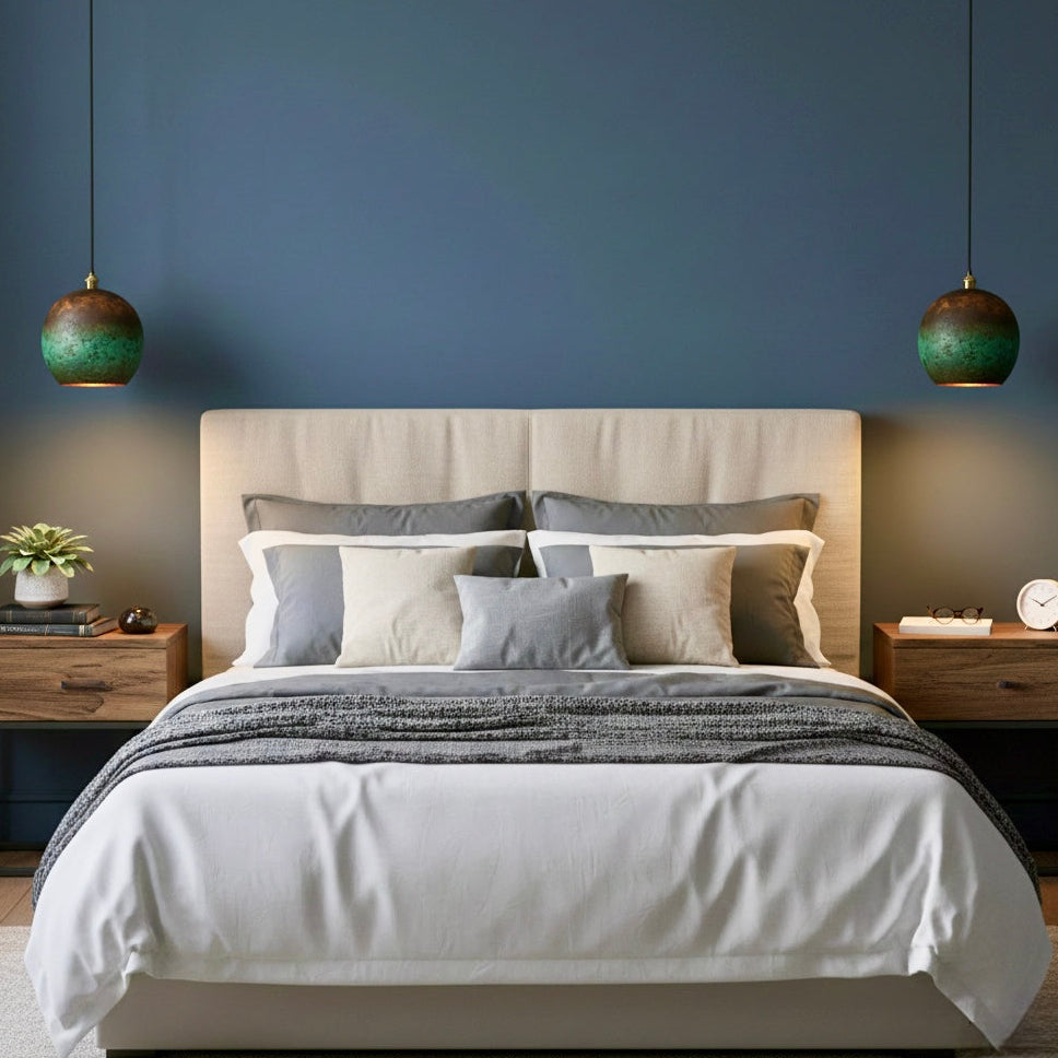 Symmetric pair of verdigris brass dome lamps providing warm bedside lighting in a modern blue bedroom.
