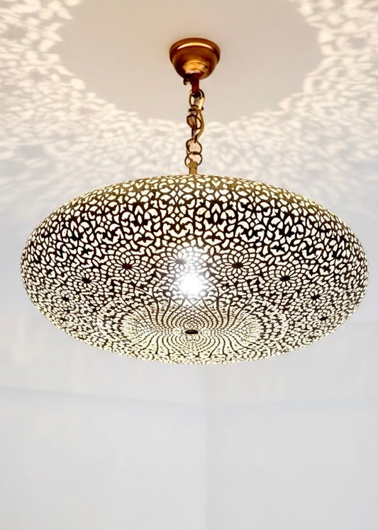 A warm-glowing Moroccan brass chandelier creating a cozy atmosphere with artistic light reflections in a minimalist interior.